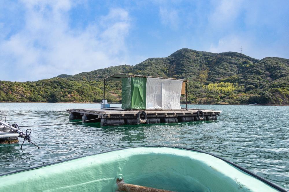 A fishing raft looks like a floating big wooden floor with a bathroom and sun shades