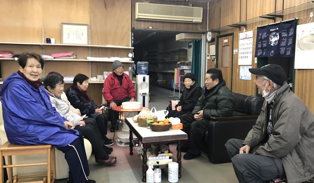   会長の今井さん（真ん中）が営むお店『いまい』にて日曜市で買ったパンや天ぷらを持ち寄ってみんなで団らん。