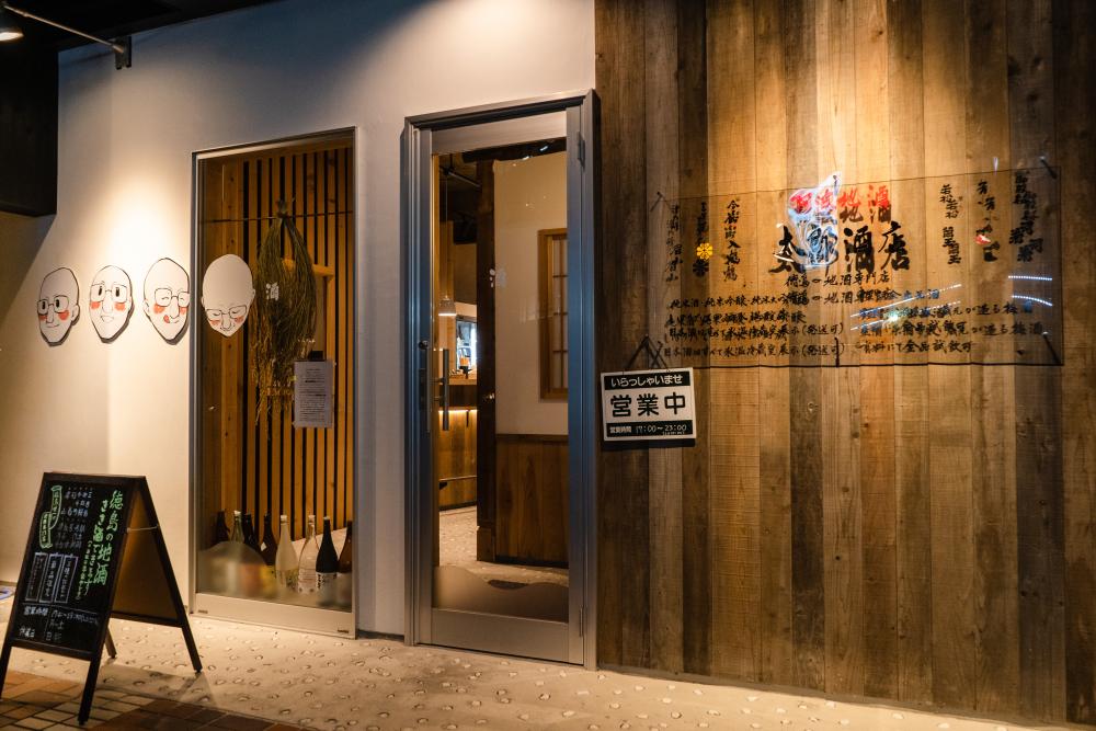 徳島の地酒が揃う太郎酒店。入り口横にはオーナーの似顔絵がある